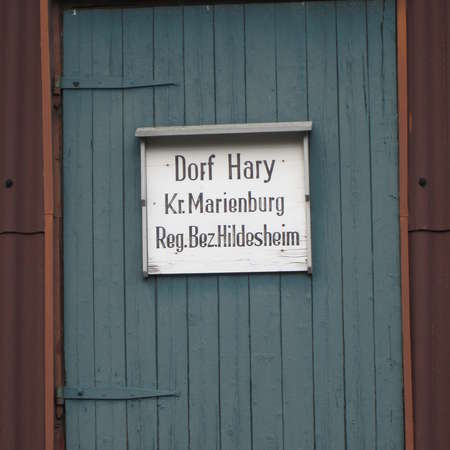 Bild vergrößern: Altes hölzernen Dorfschild an Scheunentür in Hary