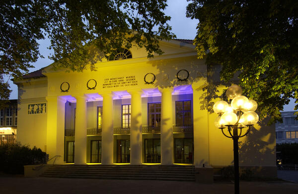 Das gelb und lila beleuchtete Theater für Niedersachsen (der Haupteingang).