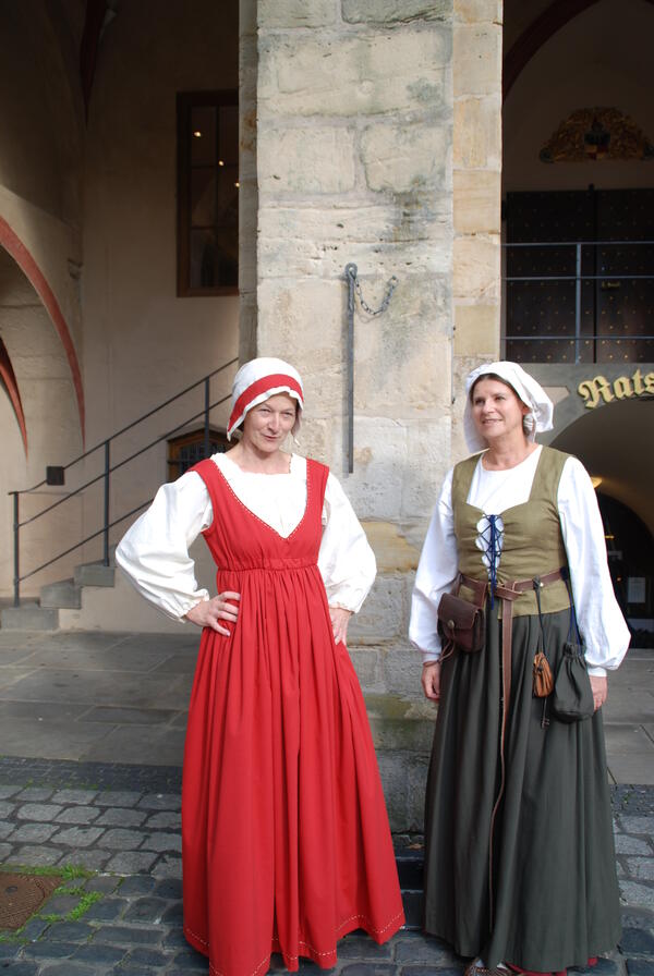 Zwei Frauen in historischer Kleidung vor einem historischen Gebäude. 