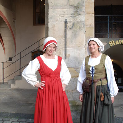 Zwei Frauen in historischer Kleidung vor einem historischen Gebäude. 